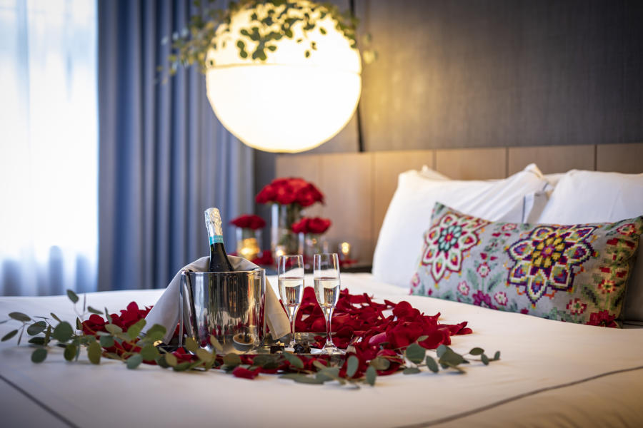 Rose petals and champagne on a hotel bed